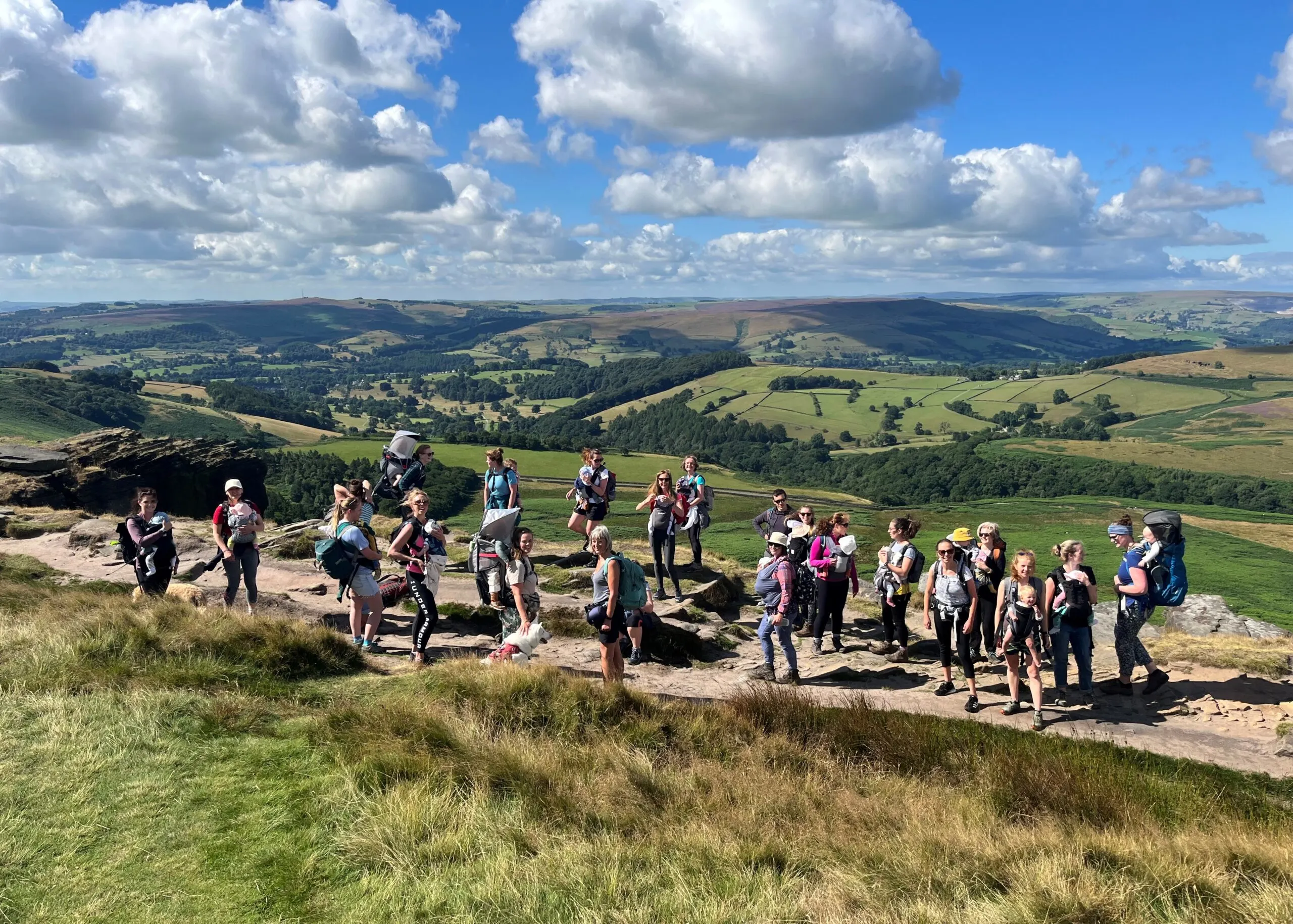 Wide landscape with a thin path climbing toward a ridge